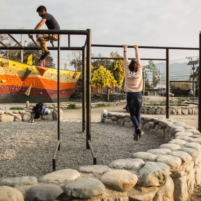 Jóvenes jugando en un pasamanos en un parque que es parte de los proyectos sociales de DeporteLibre en comunidades.