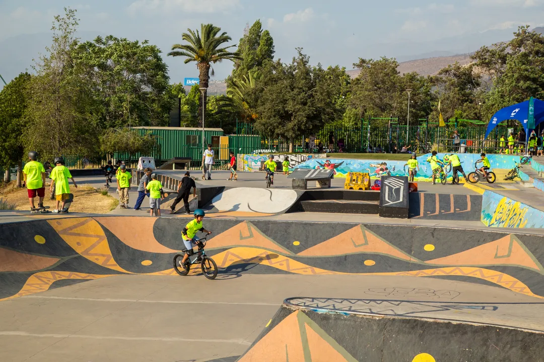 Fotografía de una estructura de color gris y amarillo donde hay niños practicando BMX con profesionales.