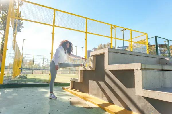 Fotografía de una mujer de pie con una pierna sobre una estructura durante entrenamiento de parkour durante el día.