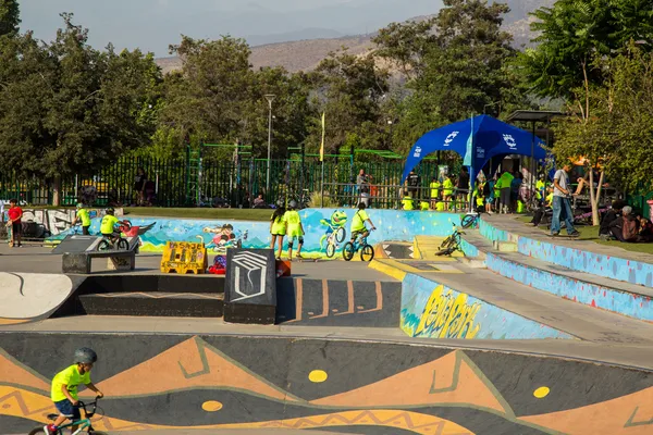Fotografía de una pista de pumptracks con muros color azul y gris con niños haciendo deporte durante el día.